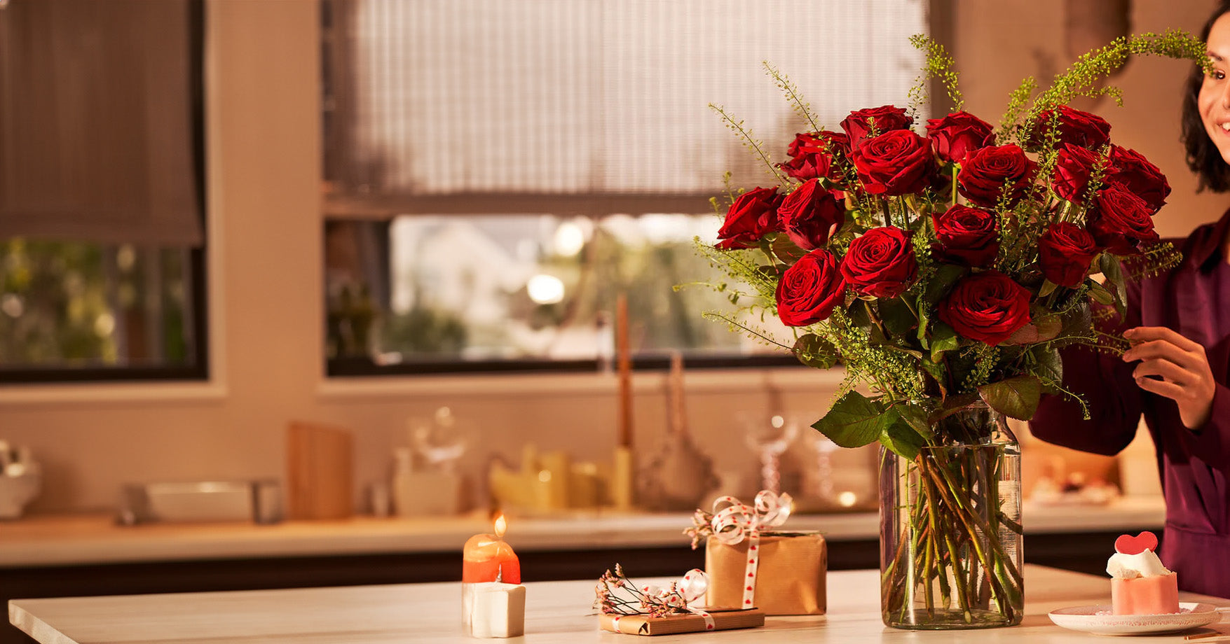Valentijnsdag boeket rode rozen in glazen vaas op tafel met cadeautjes en hartvormige cupcake