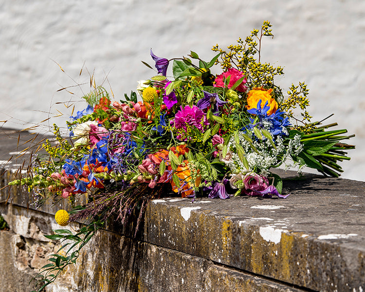 Liggend rouwboeket met kleurrijke bloemen, handgemaakt door Buurtbloemist voor een waardig afscheid.