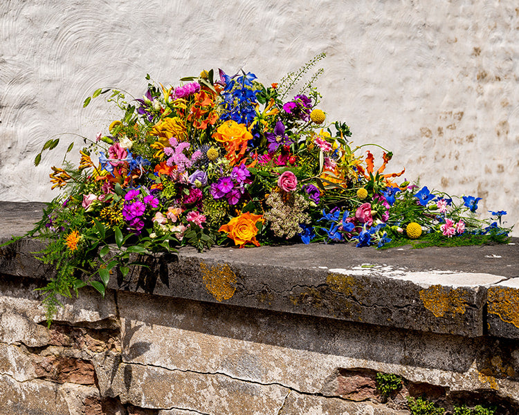 Rouwstuk in druppelvorm met kleurrijke bloemen van Buurtbloemist, geschikt voor persoonlijke afscheidsceremonies.
