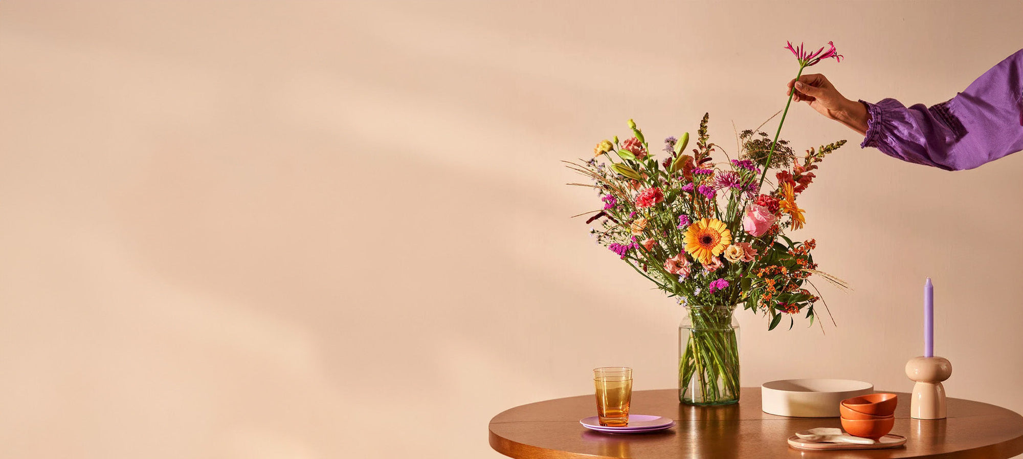 Boeket kleurrijke bloemen in glazen vaas op tafel, perfect als verjaardagscadeau.