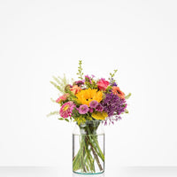 Kleurrijk klein boeket in een glazen vaas met zonnebloemen, rozen en andere bloemen.