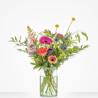 Bont gekleurd middelgroot boeket in een glazen vaas met gerbera's, rozen en andere bloemen.