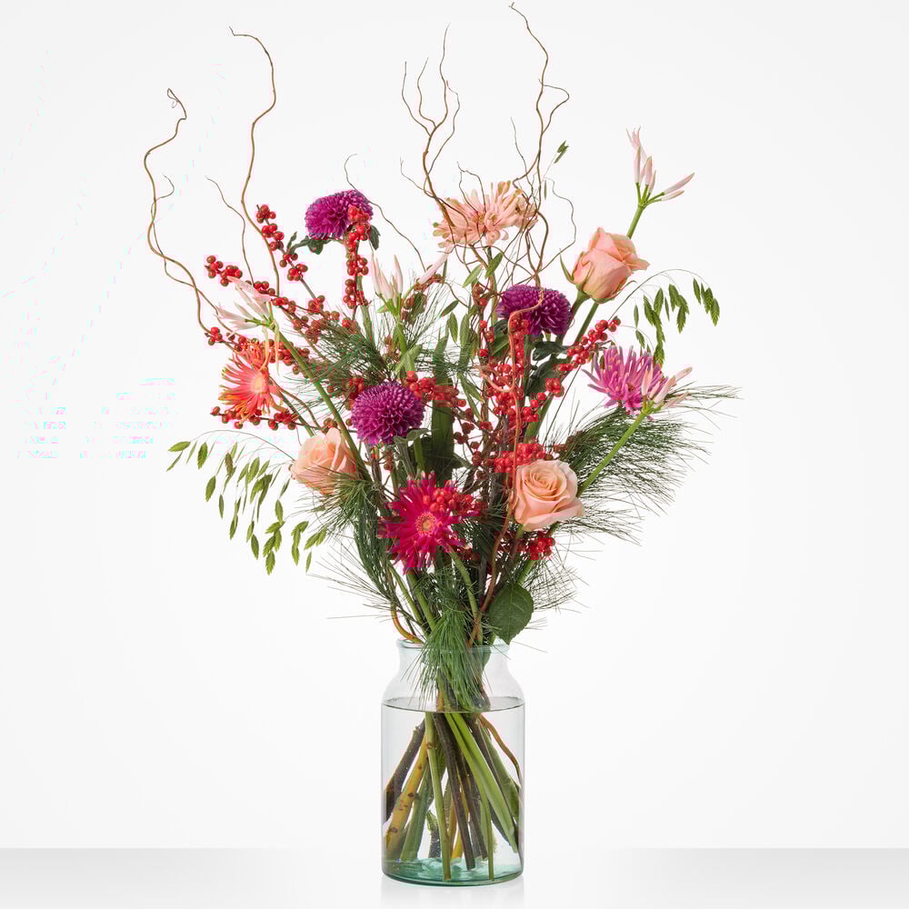 Christmas deluxe boeket met roze rozen, paarse bloemen en rode bessen in glazen vaas.