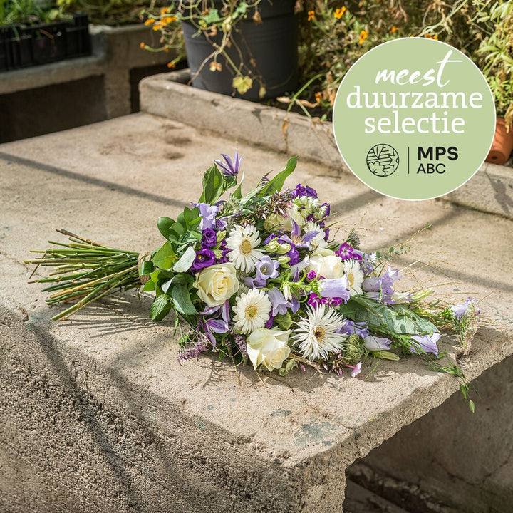 Duurzaam rouwboeket in zachte pasteltinten met witte en paarse bloemen, liggend gebonden.