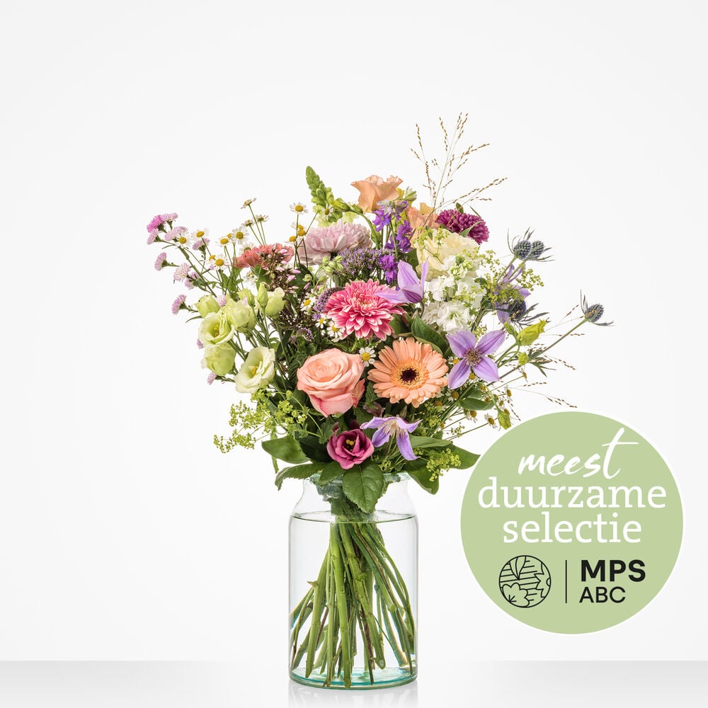 Duurzaam pastelboeket met rozen, gerbera’s en veldbloemen in glazen vaas tegen witte achtergrond