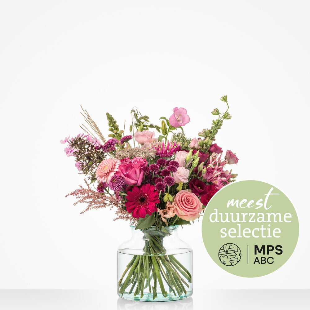 Duurzaam roze boeket met rozen, gerbera’s en lisianthus in fuchsia en zachtroze tinten in glazen vaas tegen witte achtergrond