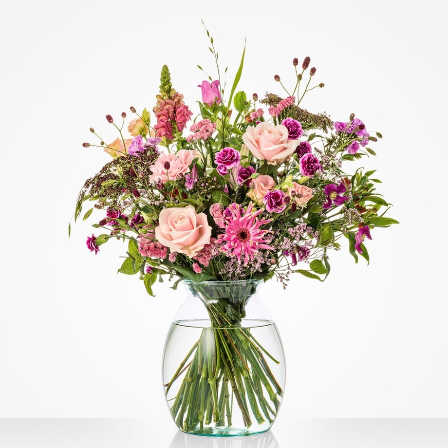 Middelgroot boeket voor een trouwdag met een mix van roze en paarse bloemen, waaronder rozen en gerbera’s, in een vaas.