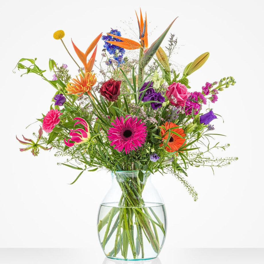 Klein boeket met een variëteit aan felle bloemen, waaronder gerbera’s, rozen, en paarse ridderspoor.