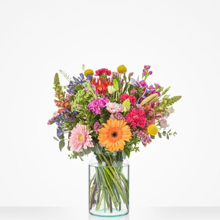 Groot boeket vol met diverse kleurrijke bloemen zoals gerbera’s, rozen, en chrysanten.