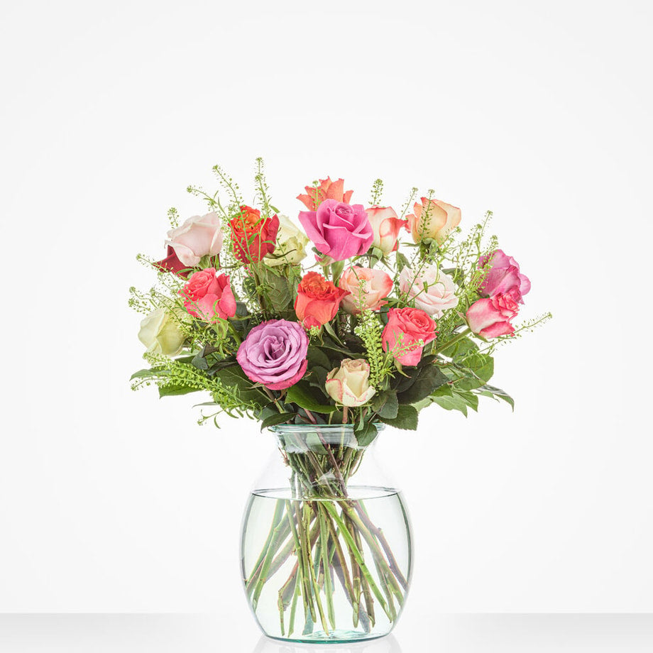 Middelgroot boeket met een mix van rozen in diverse kleuren, zoals roze, wit en paars, geplaatst in een stijlvolle glazen vaas.