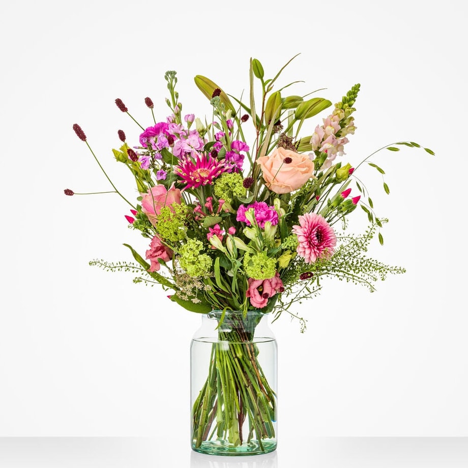 Middelgroot voorjaarsboeket met roze accenten en fris groen in vaas