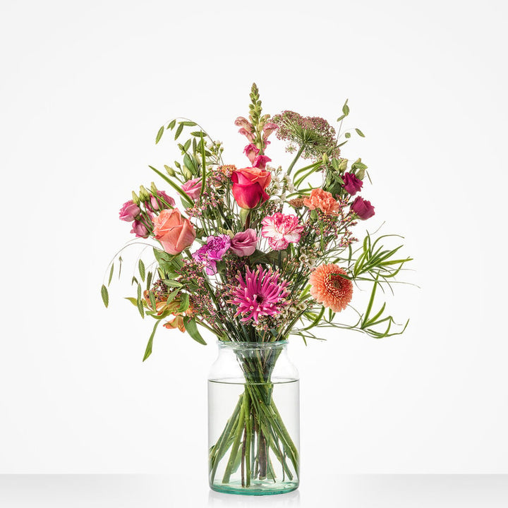 Middelgroot boeket met een mix van roze en oranje bloemen, waaronder rozen, gerbera’s en anjers