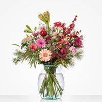 Middelgroot kerstboeket met rozen, gerbera’s en bessen in glazen vaas.