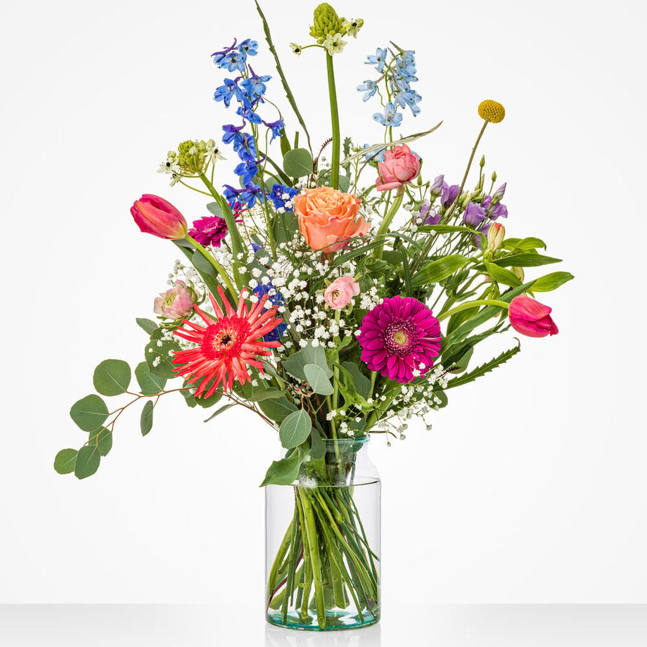 Groot april boeket met kleurrijke lentebloemen in glazen vaas