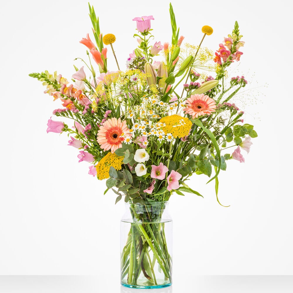Groot maandboeket juli met een uitgebreide variatie van kleurrijke bloemen zoals gladiolen, leeuwenbekjes, en gerbera’s, in een transparante glazen vaas.