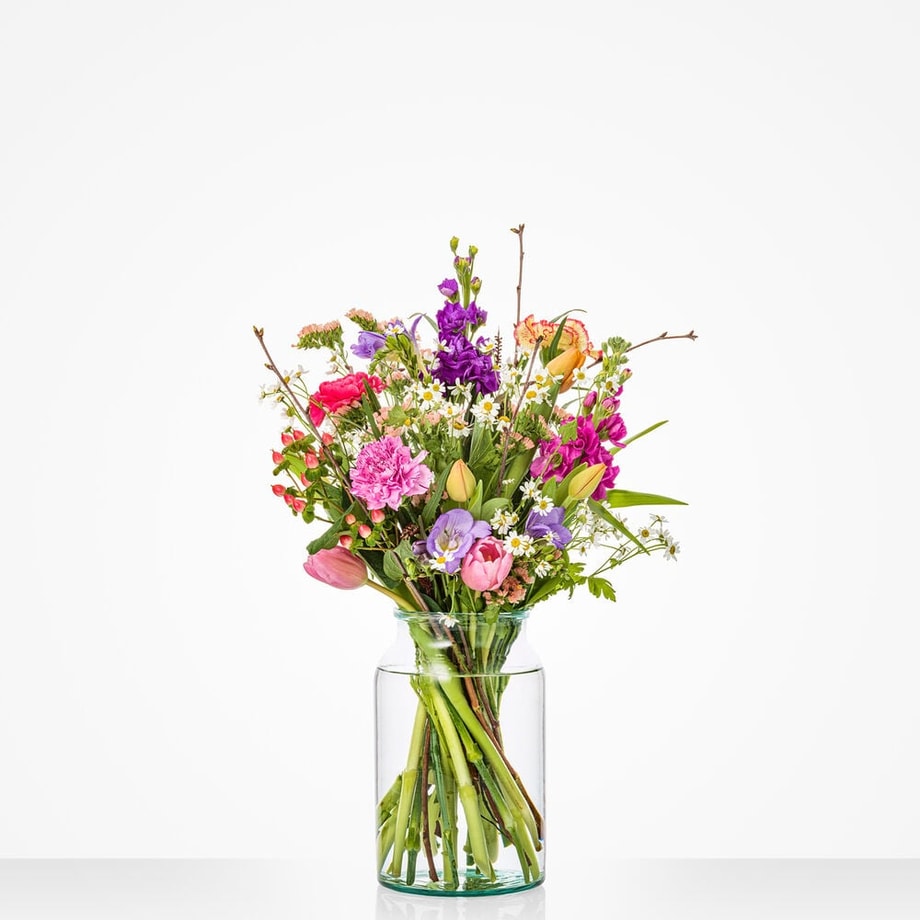 Een vrolijk klein boeket met tulpen, kamille en seizoensbloemen.