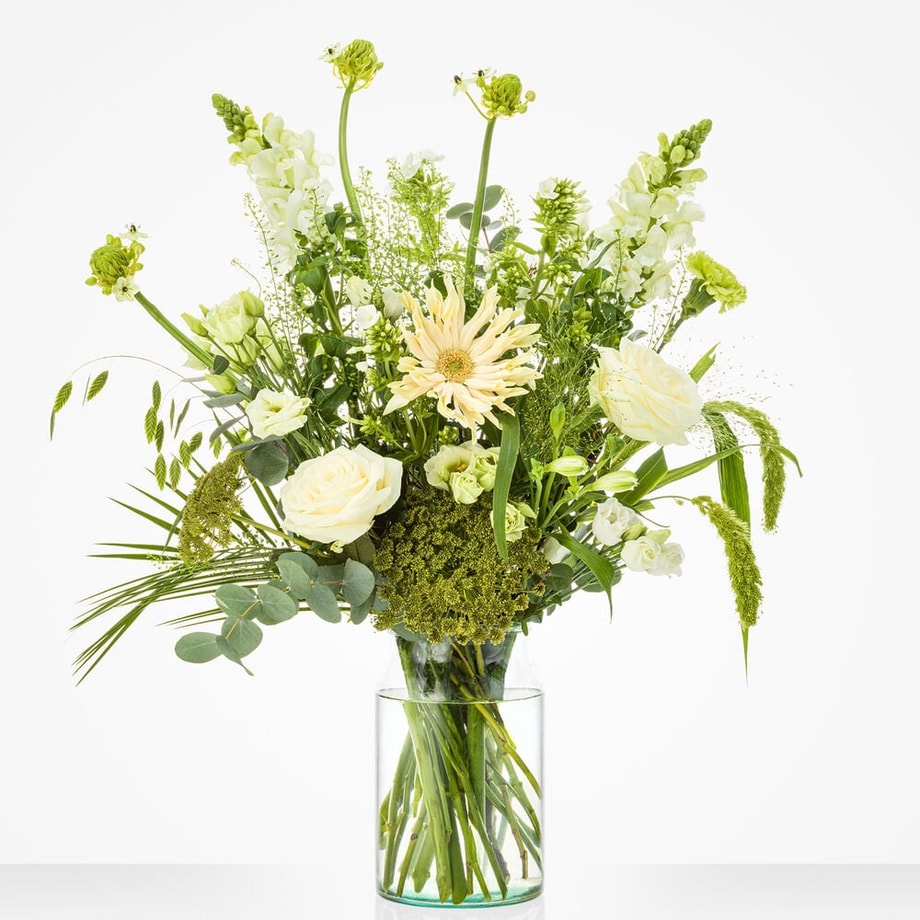 Middelgroot boeket met witte rozen, gerbera’s, snapdragons en groen blad in een glazen vaas.