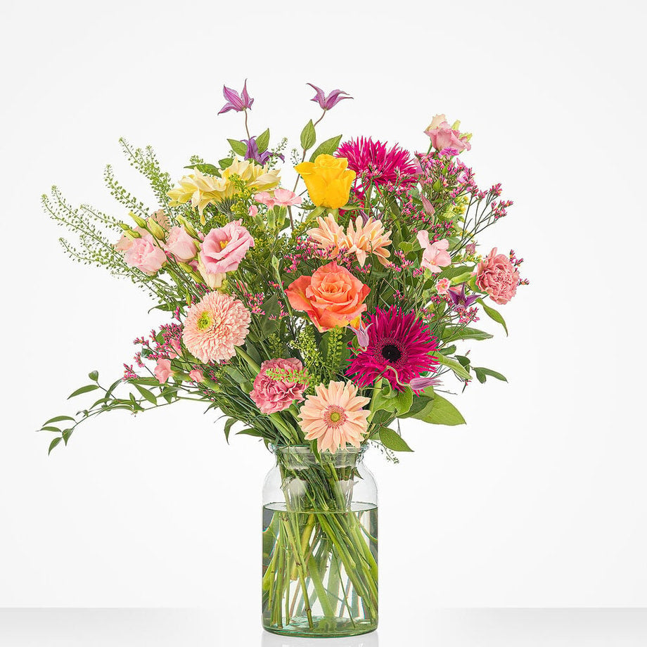 Groot boeket met vrolijke bloemen in tinten van geel, oranje en roze, waaronder gerbera’s, rozen en lisianthus
