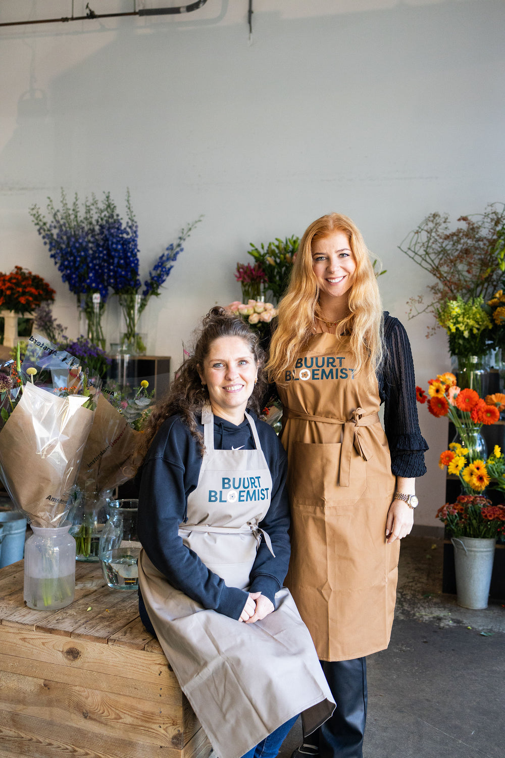 Team van Buurtbloemist in de bloemenwinkel tussen verse bloemen en boeketten.