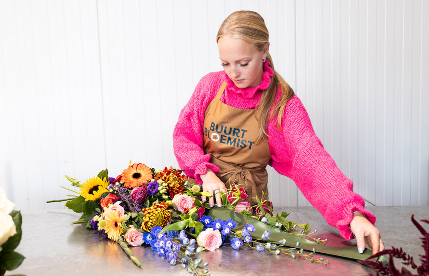 Bloemist van Buurtbloemist maakt kleurrijk rouwboeket met rozen, gerbera’s en delphinium.