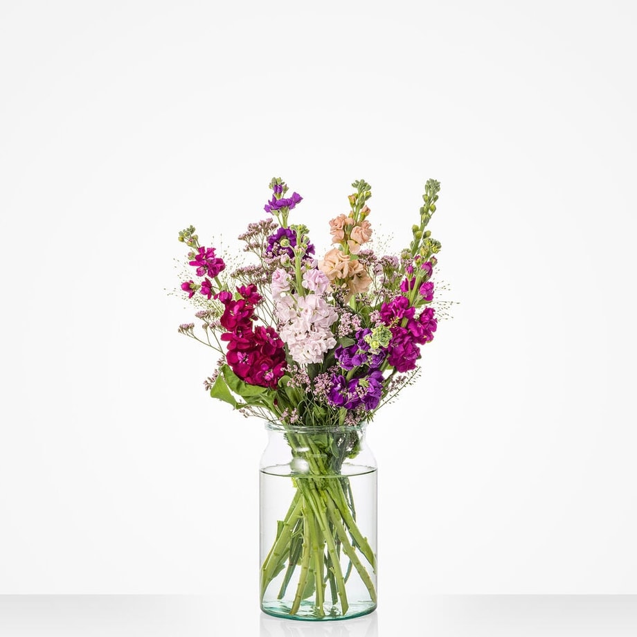 Klein boeket met violieren in paarse, roze en zalmkleurige tinten in een glazen vaas