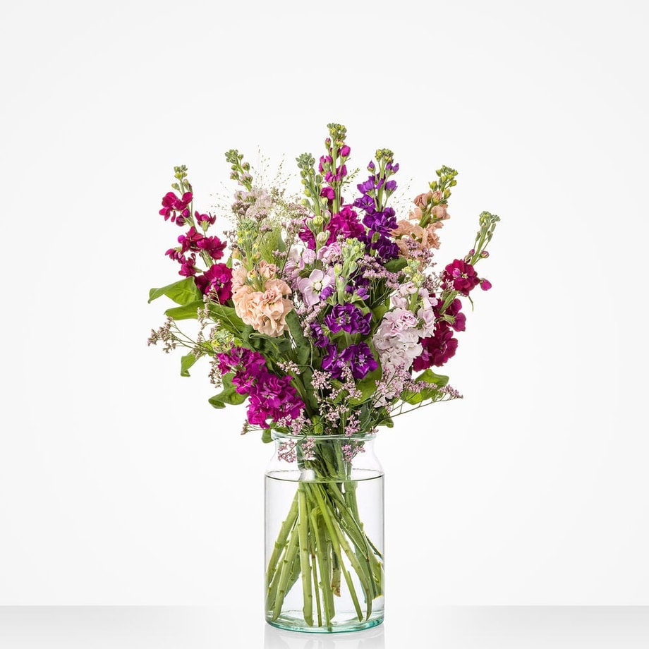 Middelgroot boeket met violieren in paarse, roze, lila en zalmkleurige tinten in een glazen vaas