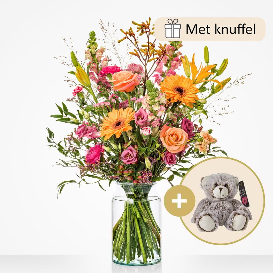 Groot boeket in een glazen vaas met een mix van bloemen zoals gerbera’s, rozen, lila bloemen, en lelies, gepresenteerd met een pluche knuffel.