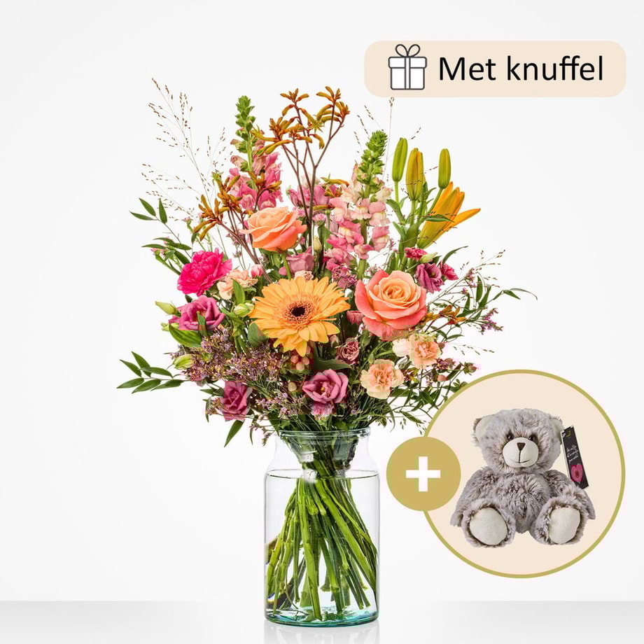 Middelgroot boeket met bloemen zoals oranje gerbera’s, roze rozen, lila bloemen, en gele lelies in een glazen vaas, gepresenteerd met een pluchen knuffel als cadeau.