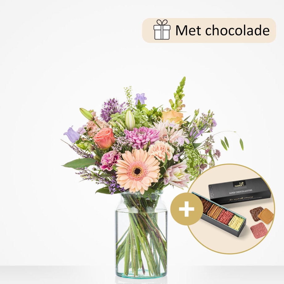 Middelgroot boeket met een variatie van bloemen zoals gerbera’s, rozen, lelies, en paarse bloemen in een glazen vaas, gepresenteerd met een doos luxe chocolade.