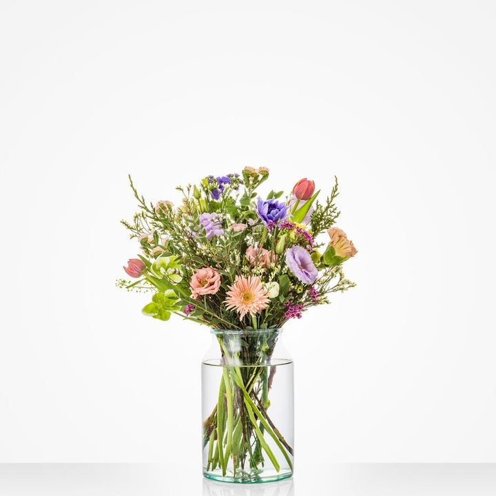 Klein winterboeket met roze rozen, paarse lisianthus en pastelbloemen in glazen vaas.