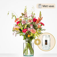 Groot boeket met een rijke mix van bloemen zoals rode rozen, gele lelies, roze gerbera’s, leeuwenbekjes en anjers, in een grote glazen vaas.