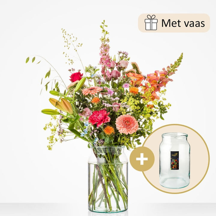Middelgroot boeket met een variatie van bloemen zoals gele lelies, roze rozen, gerbera’s, leeuwenbekjes en lila bloemen, gepresenteerd in een glazen vaas.