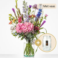 Groot boeket met een mix van bloemen zoals roze hortensia’s, blauwe riddersporen, leeuwenbekjes, en andere veldbloemen, geleverd met een grote glazen vaas.