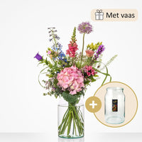 Klein boeket met een selectie van bloemen zoals roze hortensia’s, riddersporen, leeuwenbekjes, en paarse bloemen, geleverd met een glazen vaas.