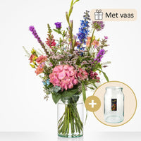 Middelgroot boeket met een mix van bloemen zoals roze hortensia’s, paarse riddersporen, leeuwenbekjes, en lila bloemen, geleverd met een bijpassende glazen vaas.