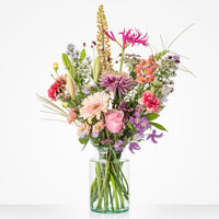 Middelgroot boeket in een glazen vaas met een mix van kleurrijke bloemen, waaronder roze gerbera’s, lelies en lichtpaarse bloemen.