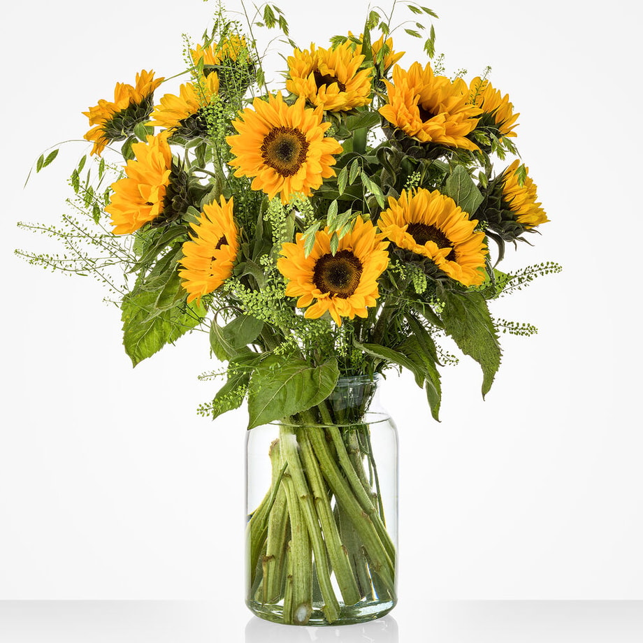 Groot zonnebloemboeket in een glazen vaas, met veertien zonnebloemen en groene bladeren.