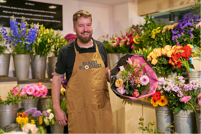 Lachende bloemist van Buurtbloemist met een veilingvers boeket in zijn bloemenwinkel in de buurt